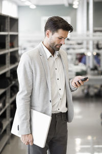 Mature businessman using mobile phone in manufacturing industry