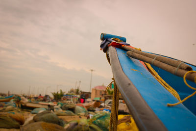 Close-up of fishing boat moored on beach against sky