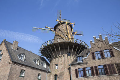 Low angle view of traditional windmill against blue sky