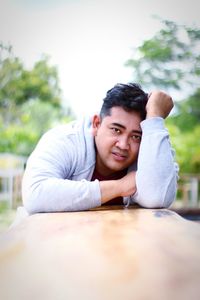 Portrait of smiling young man sitting on table