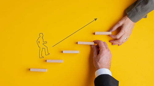 Close-up of man working on yellow table