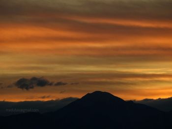 Scenic view of silhouette mountains against orange sky