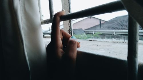 Cropped hand holding security bars on window