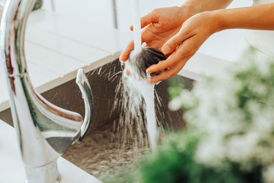 Close up of female hands washing vegetables in tap water