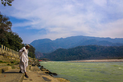 Man walking at lakeshore against mountains