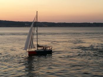 Boat sailing in sea at sunset