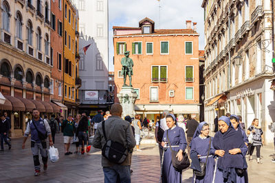 People walking on street amidst buildings in city