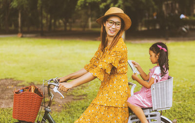 Side view of mother with daughter riding bicycle in park