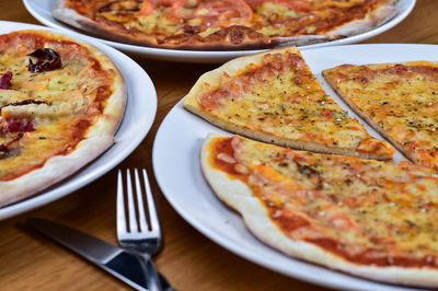 High angle view of various pizza in plates on table