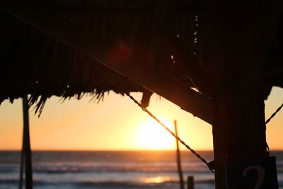 Close-up of parasol at beach during sunset