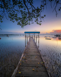 Pier over lake against sky during sunset