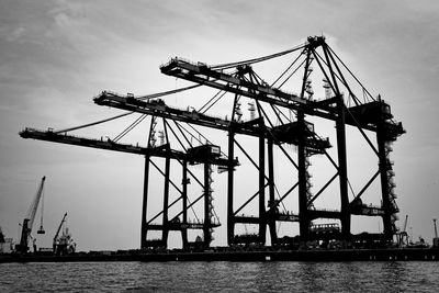 Cranes at commercial dock against sky