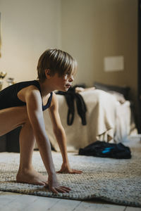 Dedicated boy exercising on carpet in bedroom at home