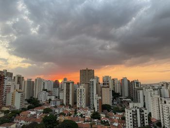 Modern buildings in city against sky during sunset