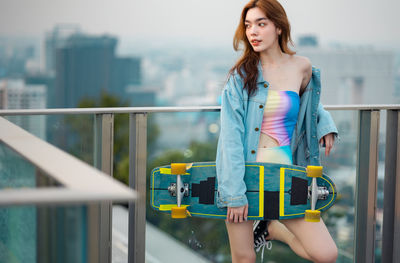 Portrait of woman standing against railing