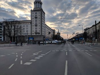 Road by buildings in city against sky