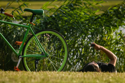 Surface level shot man lying by bicycle on grass in field