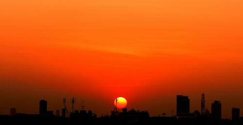 Silhouette buildings against sky during sunset