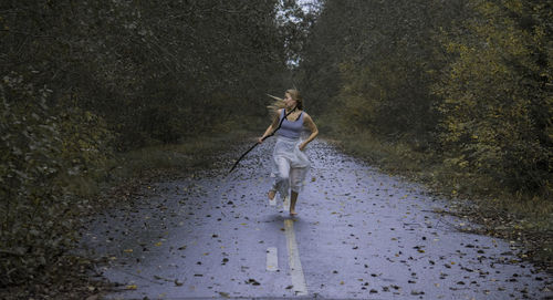 Scared young woman running on footpath in forest