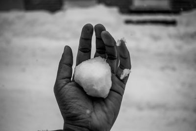 Cropped hand of man holding snow