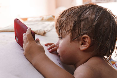 Little boy looking at the phone by the pool