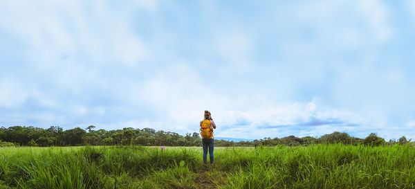 Rear view of man standing on field against sky