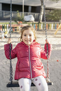 Portrait of smiling girl on swing in playground