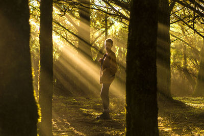 Man standing by trees in forest