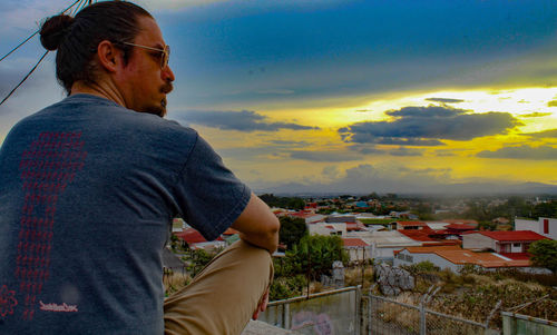 Man looking at city against sky during sunset