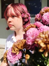 Close-up of beautiful young woman with bouquet during sunny day