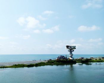 Lighthouse by sea against sky