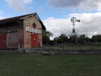 Information sign on field by building against sky