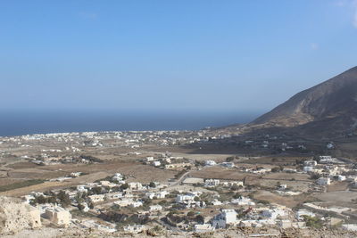 Aerial view of townscape by sea against clear sky