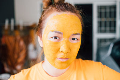 Close-up portrait of young woman with facial mask at home