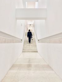 Rear view of people walking on staircase against building