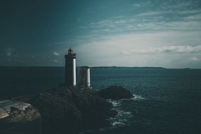 Lighthouse by sea against sky