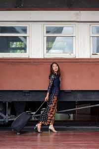 Portrait of woman standing against window