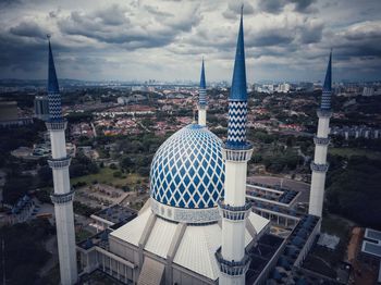 Aerial view of buildings in city against cloudy sky