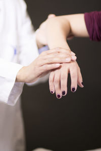 Midsection of doctor examining hand against black background