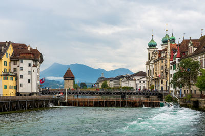 Buildings by river against sky