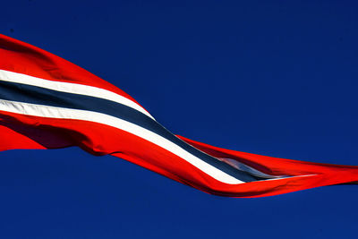 Low angle view of flag against clear blue sky