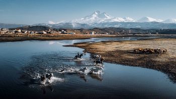 High angle view of people riding horses in lake against sky