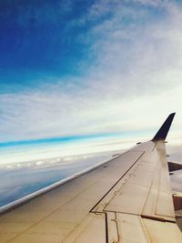 Airplane flying over clouds against blue sky