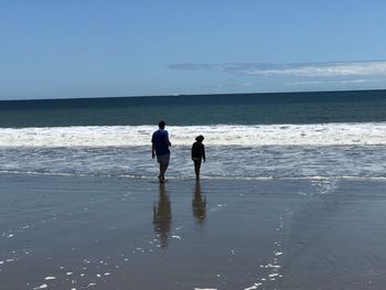 Two women on beach against sky