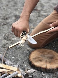 High angle view of man scraping wooden stick at campsite