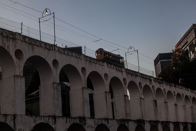 Low angle view of illuminated arch bridge against sky in city