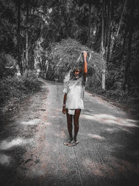 Rear view of woman standing on road in forest