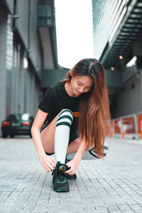 Young woman sitting on street in city