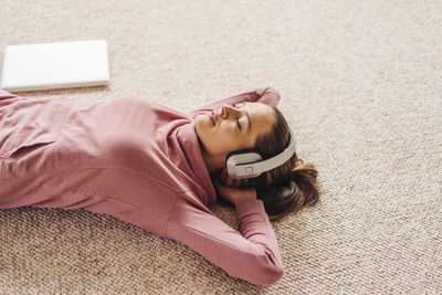 Woman lying on carpet wearing headphones