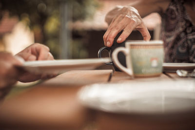 Midsection of person holding coffee cup on table
